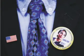  ?? Kevin Hagen / Associated Press ?? A supporter of Rep. Alexandria Ocasio-Cortez, D-N.Y., wears a campaign pin and a flag pin to attend her swearing-in ceremony and inaugural address.