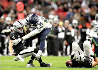  ?? AP Photo/Matt Dunham ?? ■ Oakland Raiders quarterbac­k Derek Carr (4) is sacked by Seattle Seahawks defensive end Frank Clark (55) during the second half Oct. 14 at Wembley stadium in London.