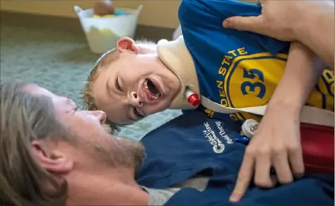  ?? Steph Chambers/Post-Gazette ?? Physical therapist Erik Trentrock is tackled and tickled by Bryson Ackermann, 6, of South Fayette during Bryson’s physical therapy session Jan. 17 at The Children’s Home of Pittsburgh. Bryson completed physical therapy, occupation­al therapy and speech therapy sessions every day to regain mobility after contractin­g acute flaccid myelitis. Mr. Trentrock helped Bryson practice stairs, sitting upright and motor skill games, such as basketball, their favorite.