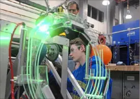  ?? Lake Fong/Post-Gazette ?? Austin DeLong, right, a junior of Chartiers Valley High School and a member of the robot team, works on a robot as team mentor Dane Bennington looks on Feb. 18 in Bridgevill­e.