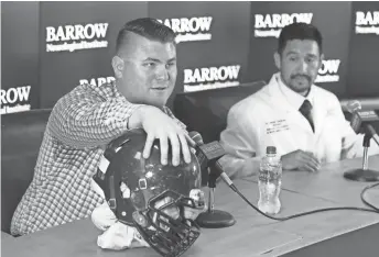  ??  ?? Former Basha High School lineman Wyatt Ellis shows his damaged helmet Friday while discussing concussion risks in sports. Lasting effects from a concussion ended Ellis’ football career.