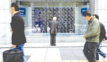  ?? — Reuters ?? A man looks at a stock quotation board outside a brokerage in Tokyo, Japan.
