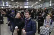  ??  ?? Waiting commuters and passengers in New York’s Penn Station look up to a train schedule board after delays were created when a train derailed earlier in the day. AP FILE