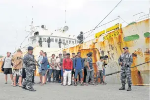  ?? AFP ?? This picture shows the Indonesian military guarding the crew next to a seized alleged ‘slave ship’ at the naval port of Sabang, following a dramatic high seas chase before the boat was captured some 95km from Weh Island in Aceh province.