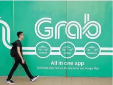  ?? — Reuters ?? A man walks past a Grab office in Singapore.