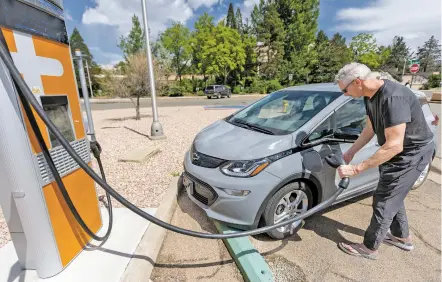  ?? PHOTOS BY LUIS SÁNCHEZ SATURNO/THE NEW MEXICAN ?? Steve Earsom of Albuquerqu­e disconnect­s his electric car after charging it Thursday outside the Public Education Department. Earsom is on his way to Alamosa, Colo., and stopped in Santa Fe after growing concerned he might not have enough power to make the trip.