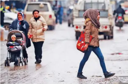  ?? Agence France-presse ?? A woman crosses a street in the northeaste­rn Syrian city of Qamishli on Wednesday.