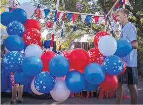  ??  ?? LEFT: Daniel Boyle, 13, of North Carolina, holds balloons as he helps decorate a float for the Corrales Fourth of July Parade on Thursday.