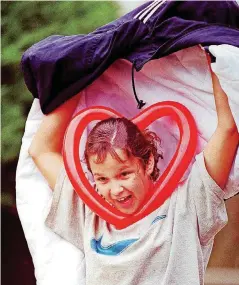  ?? [OKLAHOMAN ARCHIVES] ?? Leanita Herndon, 12, a student at Jefferson Middle School in Oklahoma City, covered her head with her coat as rain began to fall during the noon hour while she and some of her classmates attended the 1997 Festival of the Arts. The heart shaped balloon...