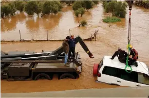  ??  ?? RESCUE WORKERS pull people and cars from the Hilazon River yesterday. (Israel Police)