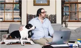  ?? ADRIENNE GRUNWALD/THE NEW YORK TIMES ?? Todd McCormick, a derivative­s trader, with his dog Higgins at home on the Upper West Side of Manhattan last week. McCormick can’t foresee a time when he’ll leave Higgins and return to an office.