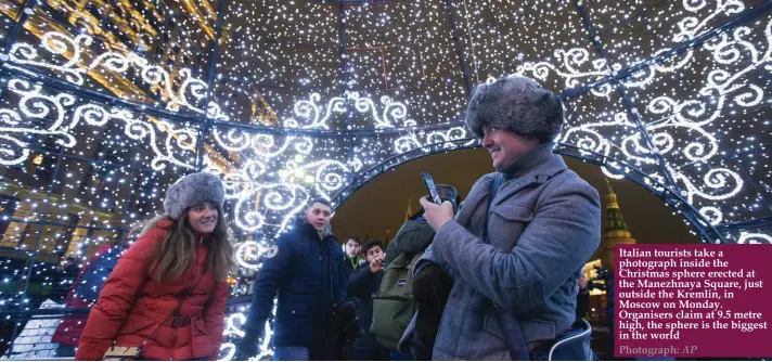 ??  ?? Italian tourists take a photograph inside the Christmas sphere erected at the Manezhnaya Square, just outside the Kremlin, in Moscow on Monday. Organisers claim at 9.5 metre high, the sphere is the biggest in the world Photograph: AP