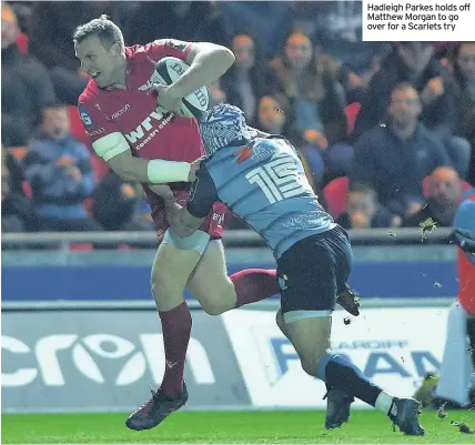  ??  ?? Hadleigh Parkes holds off Matthew Morgan to go over for a Scarlets try