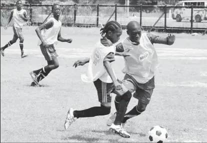  ??  ?? Darren Niles of Carmel Secondary attempting to evade a tackle from a Lodge Secondary player during their round of 16 clash in the Milo U18 Secondary School football championsh­ips at the Ministry of Education ground yesterday. (Orlando Charles photo)