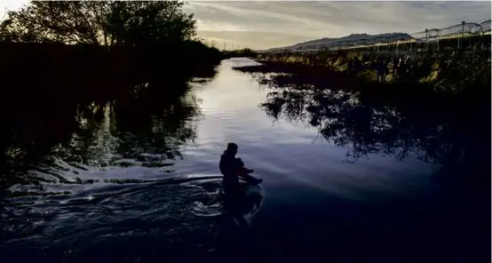  ?? JOHN MOORE/GETTY IMAGES ?? Immigrants waded through the Rio Grande while crossing into the United States from Mexico in El Paso, Texas.