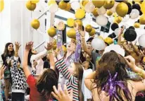  ?? ?? Sisters Blake Kurt, 10, and Kinley Kurt, 7, (center) and other children celebrate the new year while balloons are released as the clock struck noon Saturday at the Plunge’s annual event.