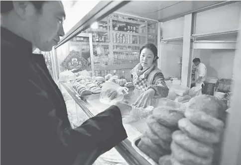  ??  ?? A customer purchases steamed buns from a vendor at a market stall in Beijing. Data released Tuesday showed China’s consumer prices rose faster than economists forecast in February after the central bank stepped up policy easing and the Lunar New Year...