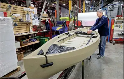  ?? Milwaukee Journal Sentinel/MICHAEL SEARS ?? Daven Claerbout, director of business developmen­t and one of the owners of Dutchland Plastics, in January checks over one of the kayaks that they make in Oostburg, Wis.