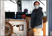  ?? (AP/Robert F. Bukaty) ?? Capt. Trent Quinby pilots the Isle Au Haut mail boat out of the harbor Wednesday in Stonington, Maine. The boat is restrictin­g it’s capacity to just six people to comply with social distancing guidelines on trips to the island 6 miles off the Maine coast.