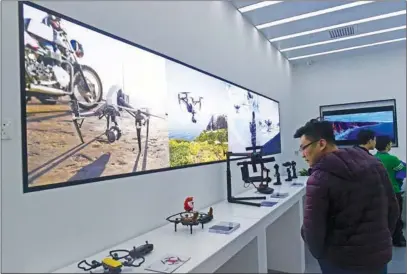  ?? PROVIDED TO CHINA DAILY ?? Customers look at unmanned aerial vehicles, or drones, at a DJI store in Tianjin, North China. Along with other innovative Chinese firms, the drone maker is pushing the developmen­t of new domestical­ly created intellectu­al property.