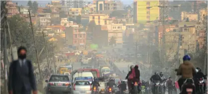  ??  ?? KATHMANDU, Madhyamanc­hal : In this photograph vehicles and motorbike riders travel on a dusty road in Kathmandu.—AFP photos