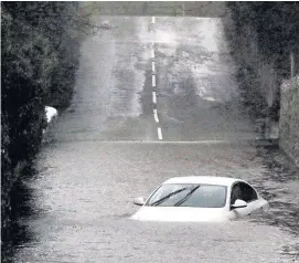  ?? Robert Parry-Jones ?? > Car partly submerged between the villages of Llanrug and Bethel, Gwynedd, on Saturday