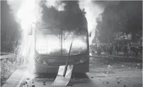  ?? — Gambar Claudio Reyes/AFP ?? MARAK: Bas terbakar semasa bantahan ganas terhadap peningkata­n harga tiket metro di pusat bandar Santiago, Chile kelmarin.