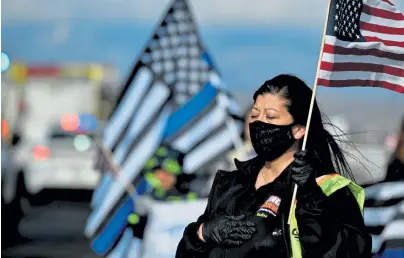  ?? Hyoung Chang, The Denver Post ?? King Soopers employee Nadine Morganflas­h holds a flag for Boulder police Officer Eric Talley as Tuesday’s procession passes by in front of the King Soopers on Colorado 7 near the corner of Sheridan Boulevard in Lafayette on Tuesday.