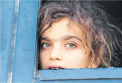  ?? IBRAHIM YASOUF/AFP/GETTY IMAGES ?? A girl from Idlib province looks out of a broken bus window duirng evacuation of residents from two pro-Assad towns Thursday.