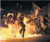  ??  ?? Riot police, left, run through fire as anti-austerity protesters throw petrol bombs in Athens; a concert at the Temple of Olympian Zeus in the capital, right