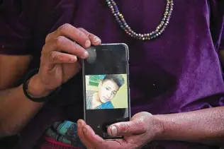  ?? Johan Ordonez / AFP/Getty Images ?? Rigoberta Vasquez, mother of 16-year-old migrant Carlos Gregorio Hernandez Vasquez, shows a picture of her son on a phone. He died in May in a Custom and Border Protection holding cell.