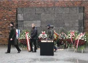  ?? CZAREK SOKOLOWSKI AP ?? People walk by the Death Wall at the Auschwitz Nazi death camp in Oswiecim, Poland, on Saturday where Holocaust survivors marked the 79th anniversar­y of the liberation of the camp.