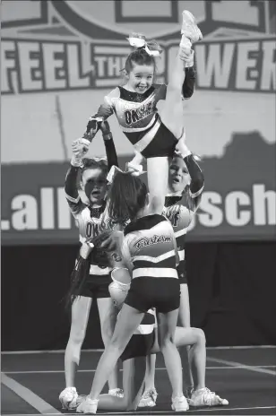  ?? Special to The Daily Courier ?? Okanagan Firestorm’s youngest competitiv­e athlete, Stevie Rossman, shows off her flexibilit­y with the help of her Mini Flames teammates in Vancouver last weekend.