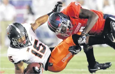  ?? [AP PHOTO] ?? Oklahoma State wide receiver Chris Lacy, left, is tackled by South Alabama cornerback Bobby Flott during the first half on Friday in Mobile, Ala.