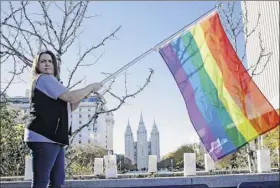  ?? Rick Bowmer / Associated Press archive ?? Sandy Newcomb poses with a rainbow flag in 2015 as people gather for a mass resignatio­n from The Church of Jesus Christ of Latter-day Saints in Salt Lake City. The church announced on Thursday it is repealing those rules that banned baptisms for children of gay parents and made gay marriage a sin worthy of expulsion.