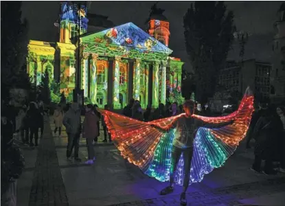  ?? NIKOLAY DOYCHINOV / AFP ?? An artist performs at a light installati­on in front of Bulgaria’s National Theatre building during the opening day of the second edition of the Lunar Festival of Lights in Sofia on May 11. Landmark buildings were illuminate­d with light installati­ons during the festival, which ended on May 14.