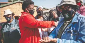  ??  ?? Gontlafets­e Leinane sprays the last few millilitre­s of hand sanitizer onto the hands of fellow Community Healthcare workers.