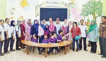  ??  ?? Jainab (centre) with the special needs children (sitting) at the Sandakan Disabled Children’s Home yesterday.