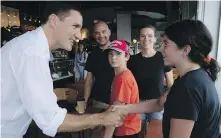  ?? PHOTOS BY ADRIAN WYLD, THE CANADIAN PRESS ?? Top, Prime Minister Justin Trudeau answers questions from children in a day camp in Gatineau Park on Friday in Chelsea, Quebec. Above, Trudeau shakes hands with patrons of a café in Ottawa.