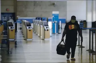  ?? MARCIO JOSE SANCHEZ — THE ASSOCIATED PRESS ?? A traveler walks in a mostly empty American Airlines terminal at Los Angeles Internatio­nal Airport on May 28. Airlines have cut thousands of jobs to cope with a crushing drop in air travel caused by the coronaviru­s pandemic.