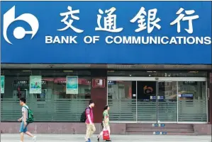  ?? ZHEN HUAI / FOR CHINA DAILY ?? Pedestrian­s walk past a Bank of Communicat­ions outlet in Nanjing, capital of Jiangsu province.