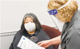  ?? JEFFREY F. BILL/ CAPITAL GAZETTE ?? Maria Grande, left, of the county immunizati­on program at the Department of Health, answers a questions from disease prevention and management deputy director Jennifer Schneider before recently receiving the first Moderna COVID- 19 vaccine in the county.