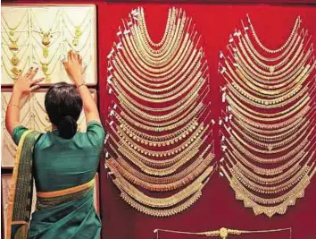  ?? Reuters ?? Losing its shine A saleswoman arranges a gold necklace in a jewellery showroom in Kochi, India. Global holdings of gold dropped 16.2 metric tonnes, the most since July 2013.