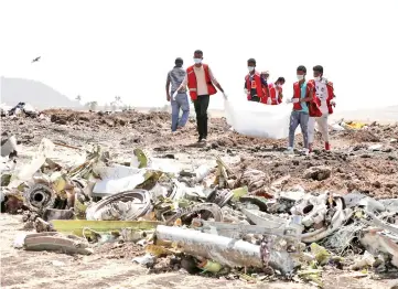  ??  ?? Ethiopian Red Cross workers carry a body bag with the remains of Ethiopian Airlines Flight ET 302 victims at the scene of the plane crash. — Reuters photos