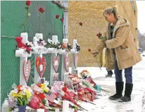  ?? NAM Y. HUH/ASSOCIATED PRESS ?? A woman places flowers at a makeshift memorial Sunday in Aurora, Ill., near Henry Pratt Co. manufactur­ing company where several were killed on Friday. Authoritie­s say an initial background check five years ago failed to flag an out-of-state felony conviction that would have prevented a man from buying the gun he used in the mass shooting.