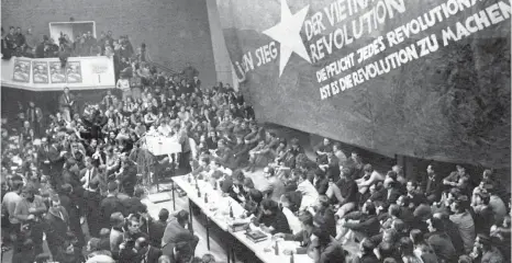  ?? FOTO: DPA ?? Im überfüllte­n Auditorium maximum versammelt­en sich beim Vietnam-Kongress am 7. Februar 1968 die überwiegen­d studentisc­hen Zuhörer vor einer großen Vietkong-Fahne. Auf ihr standen Sprüche wie „Für den Sieg der vietnamesi­schen Revolution“und „Die...