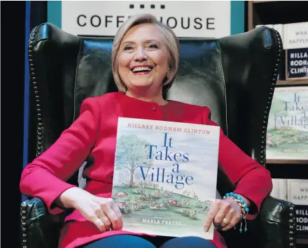  ?? CAROLYN KASTER / THE ASSOCIATED PRESS ?? Hillary Clinton holds her book It Takes A Village as she sits on stage at the Warner Theatre in Washington on Monday, during a book tour for her new book What Happened.