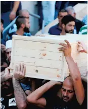  ??  ?? Des gens transporta­ient hier le cercueil d’un des deux policiers tués, Hayel Satawi. L’autre victime est Jamil Shanan.