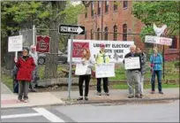  ??  ?? Demonstrat­ors against U.S. Rep. John Faso, R-Kinderhook, hold up signs outside the Kingston Library on Monday.