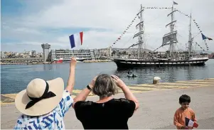  ?? | PHOTO : LOUISA GOULIAMAKI, REUTERS ?? Dans le port du Pirée, des personnes ont assisté au départ du « Belem » vers la France avec la flamme olympique à bord.